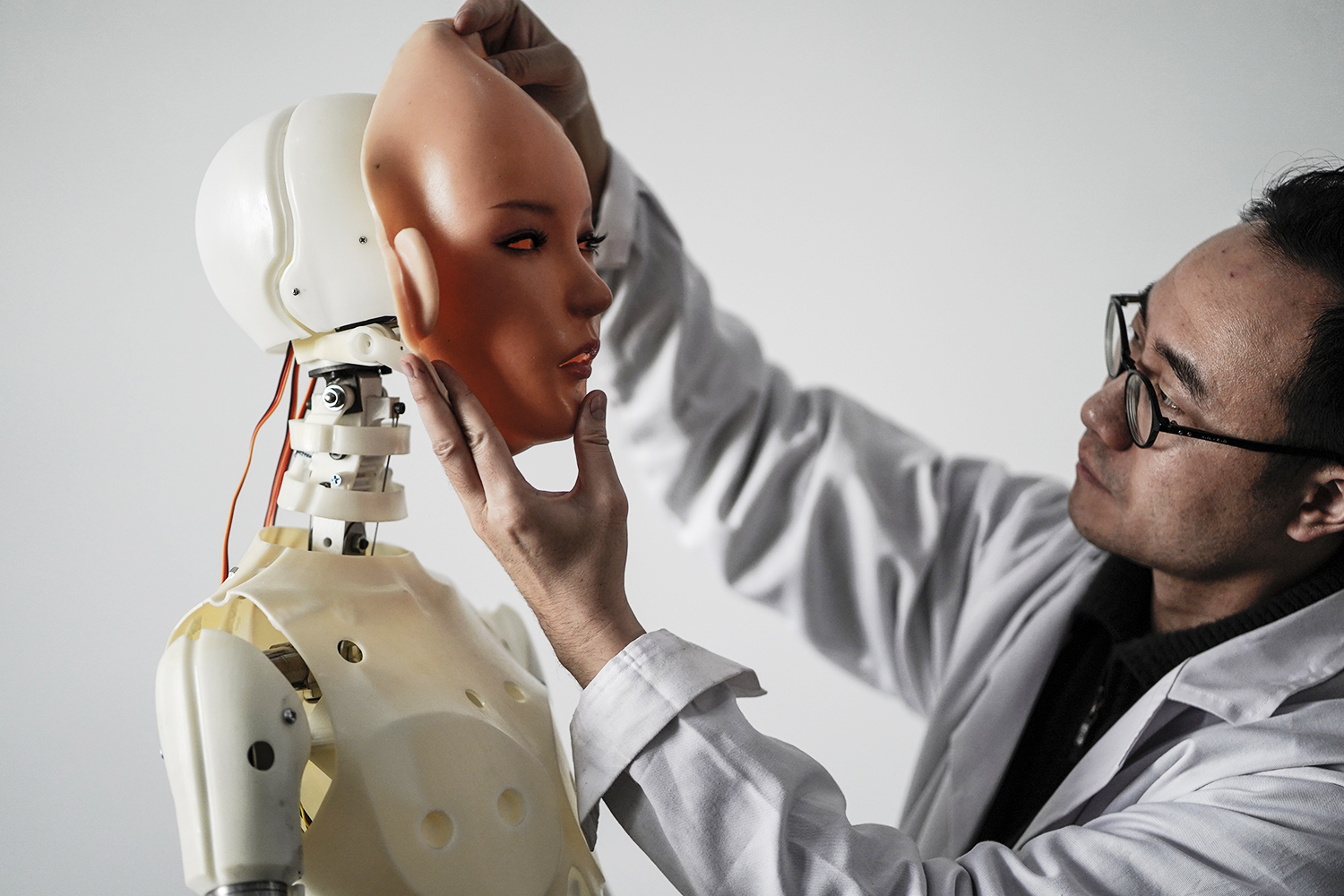 This photo taken on February 1, 2018 shows an engineer holding a silicon face against the head of a robot at a lab of a doll factory of EXDOLL, a firm based in the northeastern Chinese port city of Dalian.
With China facing a massive gender gap and a greying population, a company wants to hook up lonely men and retirees with a new kind of companion: "Smart" sex dolls that can talk, play music and turn on dishwashers. / AFP PHOTO / FRED DUFOUR / TO GO WITH China-sex-lifestyle, FOCUS by Joanna CHIU