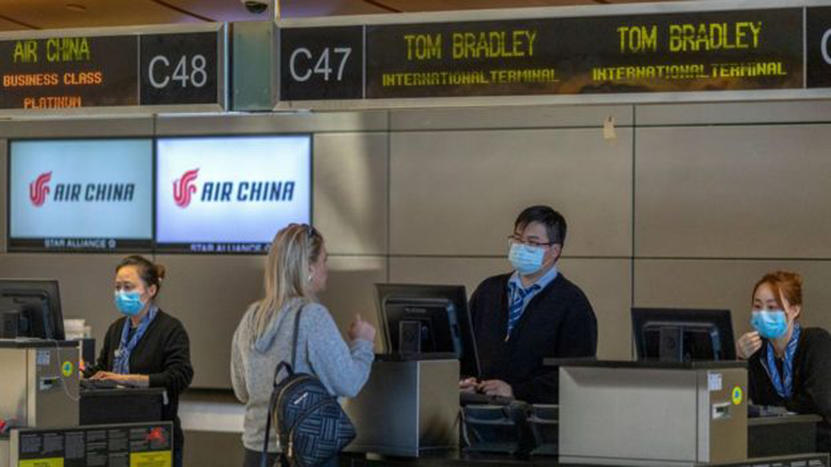 Image caption - Trabajadores de Air China en el aeropuerto de Los Ángeles se protegen del virus con máscaras