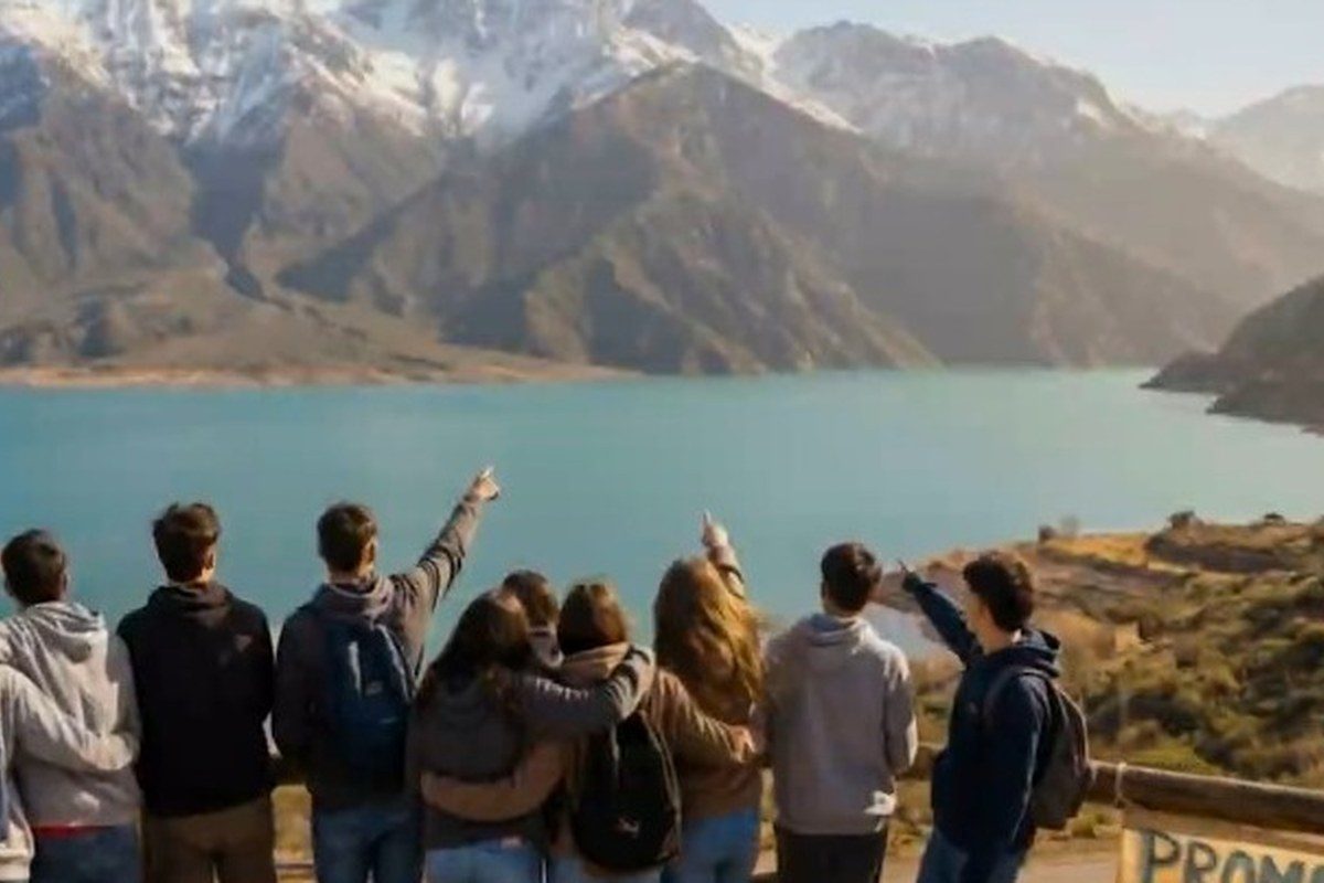 Grupo de estudiantes de viaje de egresados frente a una laguna y la cordillera en Argentina